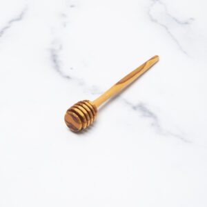 Olive wood honey dipper on a marble background