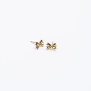 A pair of gold farfalle (bowtie) earrings sits in the center upon a plain, white surface.