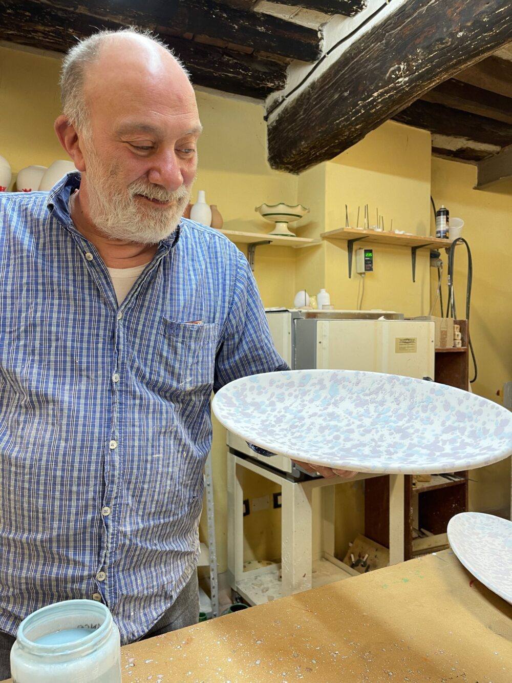 Giulio Lucarini, an Italian Splatterware Ceramicist, holds a painted platter