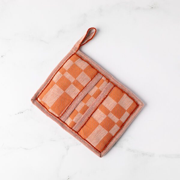 A blush checkered potholder sits on a marble background.