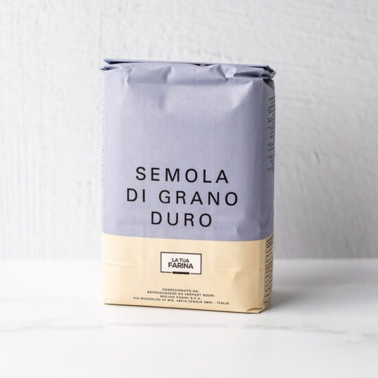 A bag of flour with the words "SEMOLA DI GRANO DURO." The top two-thirds of the bag are light purple, the bottom third is tan.